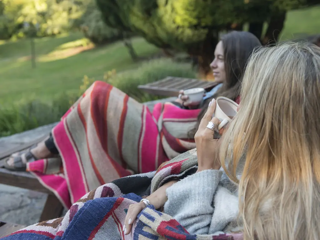 Dos personas disfrutando una infusión junto al jardín